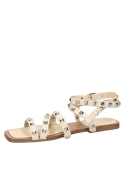 Sandalia beige de cuero con correas y tachas metálicas piramidales, estilo punk chic.