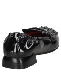 Mocasín de cuero negro para mujer, con acabado brillante y detalle de tachas, ideal para un look audaz.