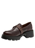 Calzado robusto en cuero café con textura de reptil y tachas metálicas, ideal para un estilo casual urbano.