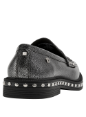Zapato mocasín de cuero plateado, estilo tachas, estructura clásica con empeine liso y elementos geométricos distintivos.
