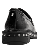 Elegante mocasín de cuero negro para mujer, con empeine liso y detalles metálicos que aportan un aire contemporáneo.