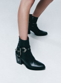 Botín negro de cuero para mujer con textura de reptil y tachas, estilo western, ideal para un look elegante y robusto.
