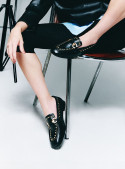 zapato mocasín negro de cuero para mujer con adorno metálico en el empeine y tachas decorativas en el borde superior