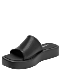 Sandalia de cuero negro minimalista para mujer con banda ancha y adorno metálico discreto.