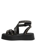 Sandalia negra de cuero con plataforma y tiras cruzadas, hebilla dorada ajustable para un look urbano.
