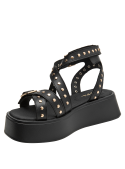 Sandalia de mujer negra de cuero con diseño gladiador y apliques metálicos dorados, estilo casual rockero.