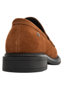 Mocasín de cuero café para mujer con textura de gamuza y adorno metálico en la parte superior.