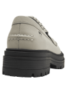 Mocasín de cuero beige para mujer con tachas metálicas en el empeine y flecos, estilo casual y moderno.