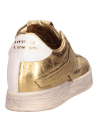 Zapatilla femenina oro de cuero, perfil limpio y costuras definidas.