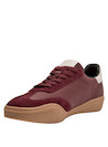 Zapatilla urbana burdeos de cuero suave con textura de gamuza y detalles metálicos.