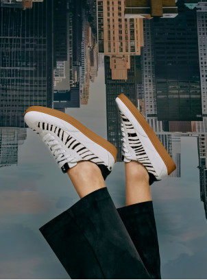 Zapatilla blanca de cuero para mujer con detalle de cebra, estilo urbano y diseño moderno.