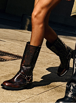 Bota de cuero moreno para mujer con diseño urbano y detalles metálicos.