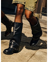 Botas urbanas de cuero negro para mujer con detalles metálicos que destacan su diseño audaz.