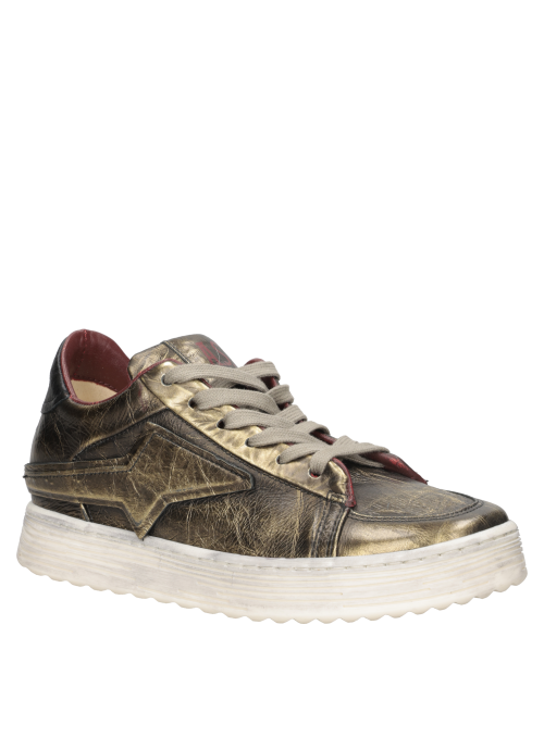 Zapatilla de mujer en cuero suave dorado, perfecta para combinar con jeans ajustados y blusas elegantes.