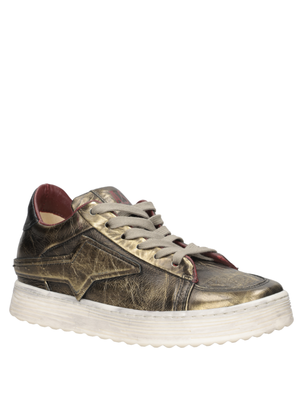 Zapatilla de mujer en cuero suave dorado, perfecta para combinar con jeans ajustados y blusas elegantes.