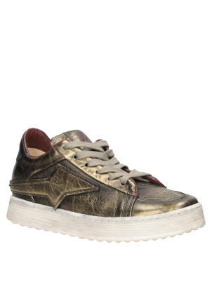 Zapatilla de mujer en cuero suave dorado, perfecta para combinar con jeans ajustados y blusas elegantes.