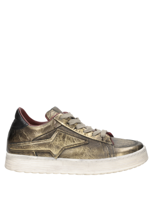 Zapatilla urbana dorada para mujer, con acabados sofisticados y costuras visibles que destacan su diseño.